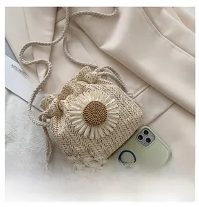 Top view of straw woven bucket bag with daisy flower detail and long braided strap