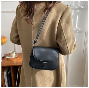 Detail view of the black leather saddle bag shown on a model in a minimal setting