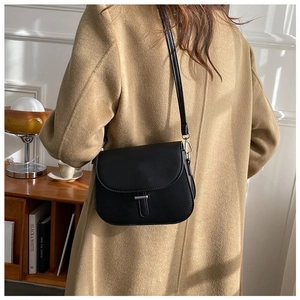 Minimalist black leather saddle bag shown on a model side-profile with metal details