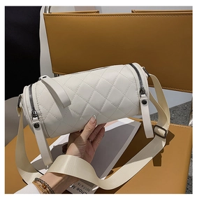 Detail of white quilted barrel crossbody bag with adjustable strap held by hand