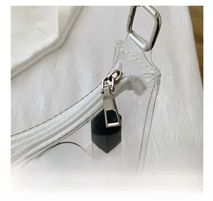 Close-up of smooth silver zipper hardware and transparent PVC texture of the shoulder bag