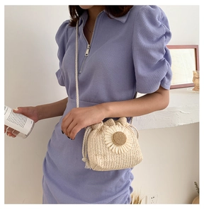 Detail of hand-woven straw bucket bag with sunflower decor and drawstring closure