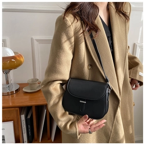Detailed view of a black minimalist saddle bag featuring a sleek silver metal buckle
