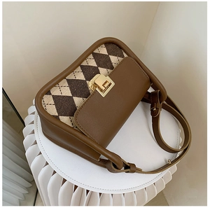 Close-up of vintage plaid saddle bag featuring brown leather trim and golden clasp