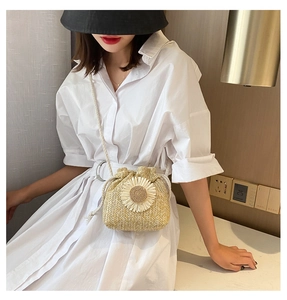 Close-up of woven straw bucket bag featuring a white sunflower design and drawstring closure