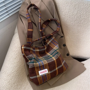 Classic plaid tweed tote bag with shoulder strap and fashion label on warm wool blazer
