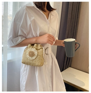 Detail of hand-woven straw bucket bag featuring a 3D sunflower and drawstring closure