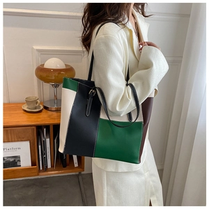 Dettaglio di una borsa tote grande color-block con finiture dorate e tracolla sottile elegante