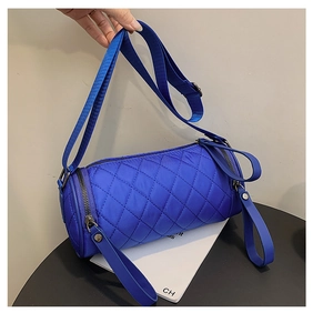 Detail of royal blue quilted cylinder bag with rhombus pattern and adjustable strap