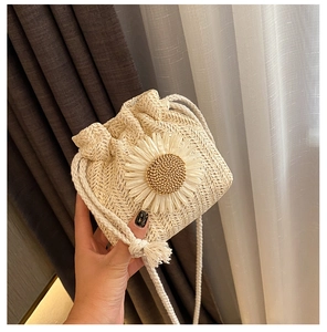 Close-up of a woven straw bucket bag featuring a large white daisy flower detail
