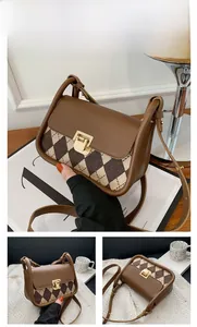Detail view of vintage brown plaid saddle bag with leather strap and gold buckle