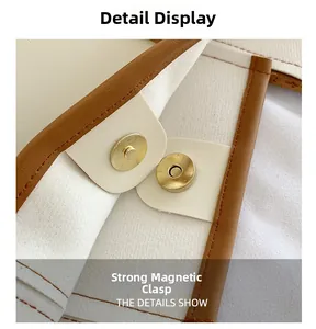 Detail of the strong gold magnetic buckle on a cream faux leather tote bag with brown trim
