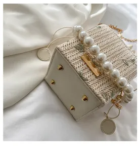 Détail du fond d'un sac en paille tissée avec clous dorés et anse en perles