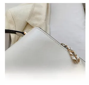 Detailed close-up of a white leather handbag with precise stitching and gold chain strap