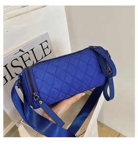 Macro detail of royal blue quilted nylon cylinder bag with wide strap and zip