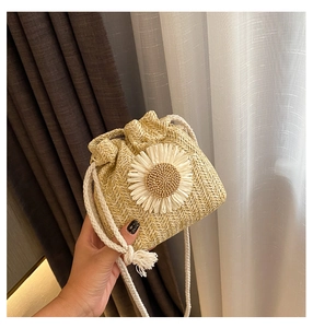Detail of hand-woven straw bag featuring a large 3D white daisy and cotton drawstring strap
