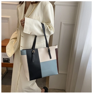 Dettaglio della borsa tote in pelle color-block con fibbia in metallo dorato e tracolla nera