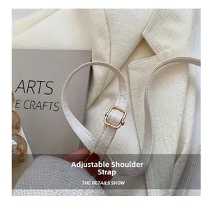 Detail of adjustable shoulder strap with gold metal buckle on a beige fashion bag