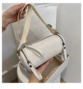 Detail of quilted beige barrel bag with adjustable strap and leather zip puller