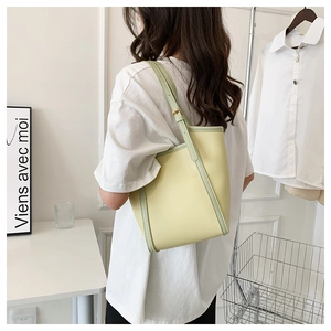 Detail of light yellow bucket bag with green contrast edges and minimalist shoulder strap