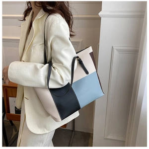 Dettaglio della borsa tote color-block con cuciture bianche e chiusura a zip sulla spalla