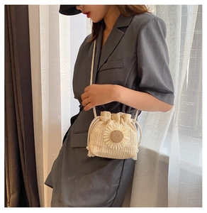 Detail of straw woven bucket bag with daisy flower and drawstring strap on model