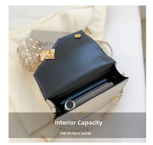 Detail view of the spacious inner compartment of the black and white chain crossbody bag