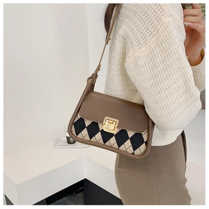 Close-up of vintage argyle pattern saddle bag with brown leather flap and gold metal clasp