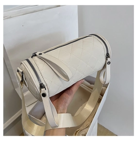 Close-up of beige quilted nylon cylinder bag with wide shoulder strap and black zipper