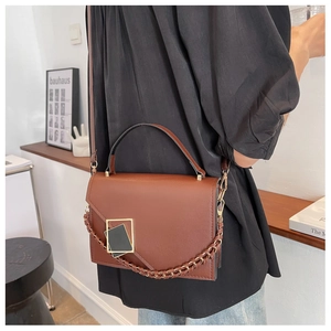 Close-up of brown leather handbag featuring a gold square buckle and chunky metal chain