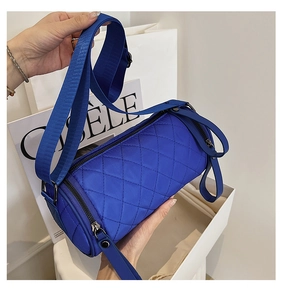 Close-up of quilted nylon cylinder crossbody bag in bright blue with adjustable strap