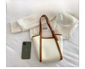 Detail of minimalist tote bag in cream leather with brown trim and shoulder strap