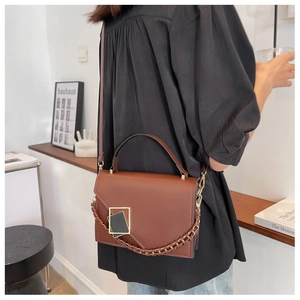 Detail of vintage brown crossbody bag featuring metal square buckle and chain strap