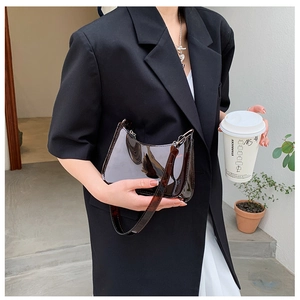 Detail of a vintage dark brown glossy patent leather shoulder bag with a silver metal buckle