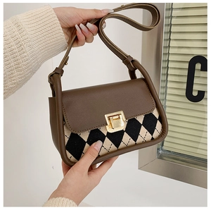 Detail of vintage saddle bag featuring brown leather and black white plaid pattern texture