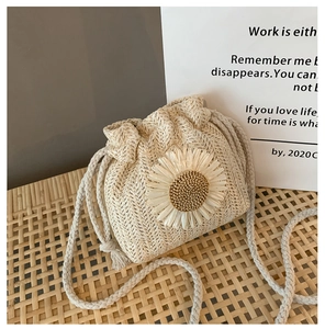 Detailed view of straw woven bucket bag with 3D daisy flower and drawstring closure