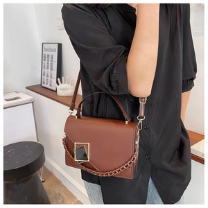 Brown retro flap crossbody bag with golden buckle and chain on a female model