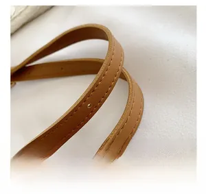 Close-up of brown leather shoulder strap featuring precise stitching and adjustable holes