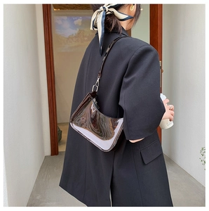 Close-up of black patent leather shoulder bag with silver hardware and glossy finish