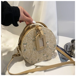 Detail of round straw crossbody bag with floral embroidery and adjustable strap