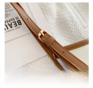 Detail of adjustable brown leather shoulder strap with gold buckle and fine stitching
