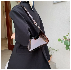 Detail of dark brown glossy patent leather hobo bag with sleek metal strap buckle