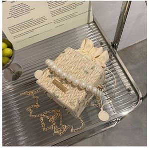Détail du sac seau en paille beige avec broderie florale, poignée perle et cordon