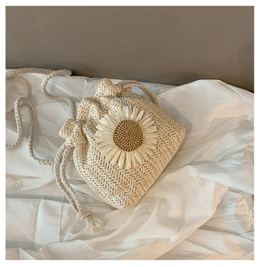 Detailed texture of hand-woven straw bucket bag featuring a large daisy floral accent