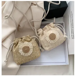 Detail of mini straw bucket bags with daisy decor and woven straps in natural tones