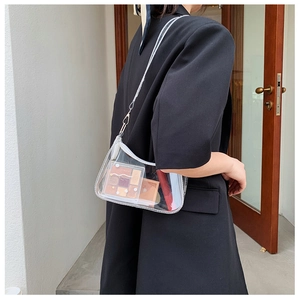 Detailed view of clear PVC shoulder bag showing capacity with cosmetics and white trim