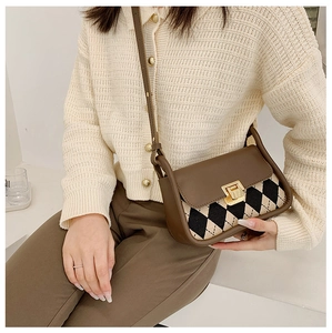 Close-up of vintage plaid saddle bag featuring a brown leather flap and golden metal clasp