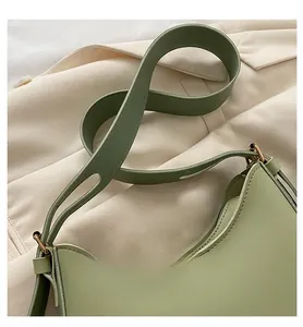 Detail of light green leather crescent bag with wide shoulder strap and gold buckle