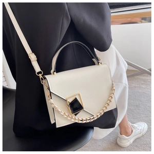 Detail of white leather shoulder bag with geometric hardware and woven chain strap