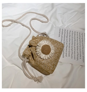 Detail view of handmade straw bag with large white daisy floral accent and drawstring top